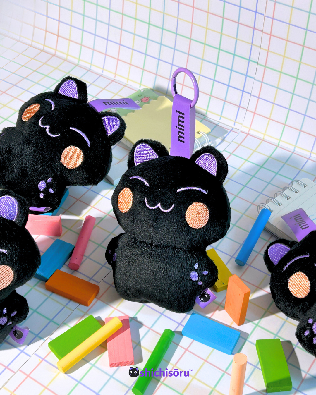 Black cat plush toys with purple accents on a colorful grid background