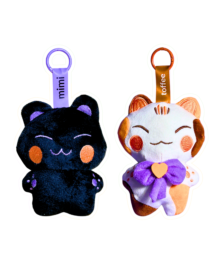 Two plush keychains, one black and one orange with a white face, on a white background.